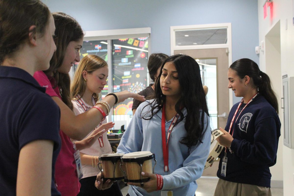 Eighth graders Juliana Alonso and Sonia Murugesan  bang on the Tambor at the Puerto Rico stand.